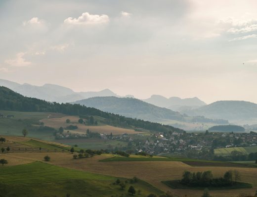Aerial view of a peaceful countryside with rolling hills and fog in the distance, perfect for a tranquil escape.
