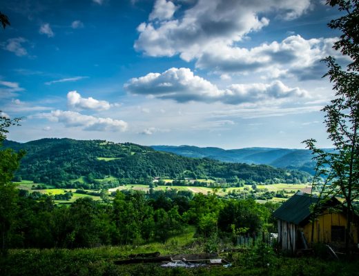 A picturesque countryside landscape featuring lush green hills under a bright blue sky.