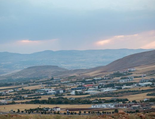 A serene view of Elazig's countryside with hills and fields under a pastel sky at dusk.