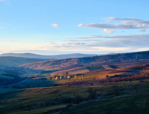 Beautiful landscape of rolling hills with soft sunset lighting and scattered clouds.