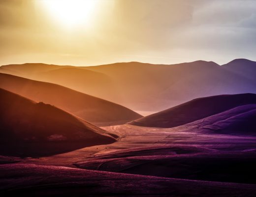 Dramatic landscape of sunset over Montemonaco's hilly terrain, showcasing vibrant natural beauty.