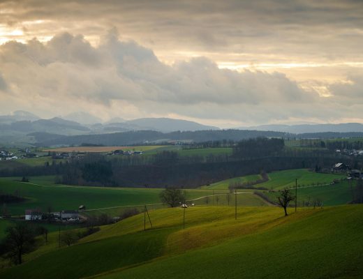 Breathtaking view of rolling hills and fields under a dramatic sunset sky.