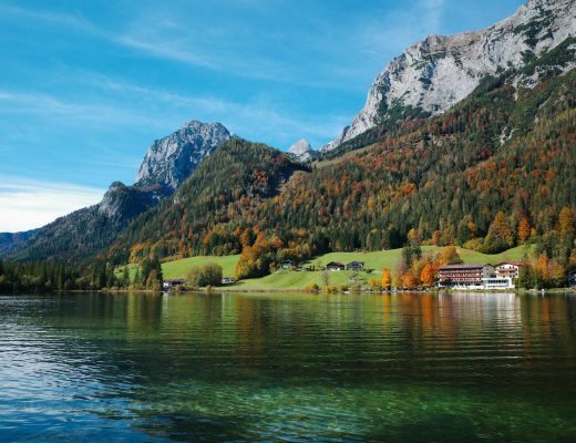Picturesque autumn landscape of Hintersee Lake with vibrant foliage and majestic mountains in Germany.