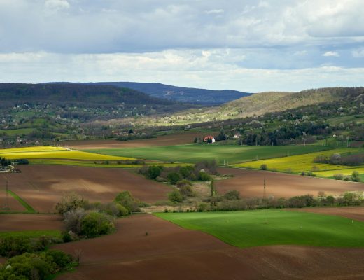 Aerial view of rolling hills and green fields in Nagygรถrbล, Hungary, showcasing pastoral beauty and tranquility.