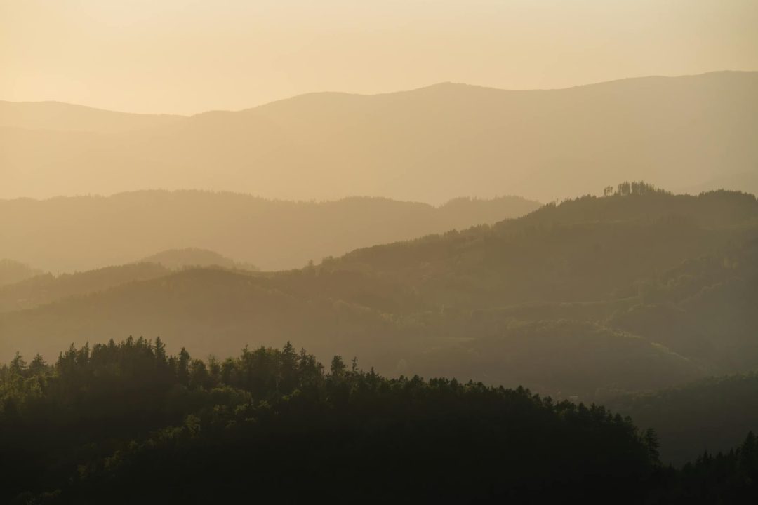 Capture the tranquil layers of Graz's rolling hills at sunset, radiating a peaceful ambiance.