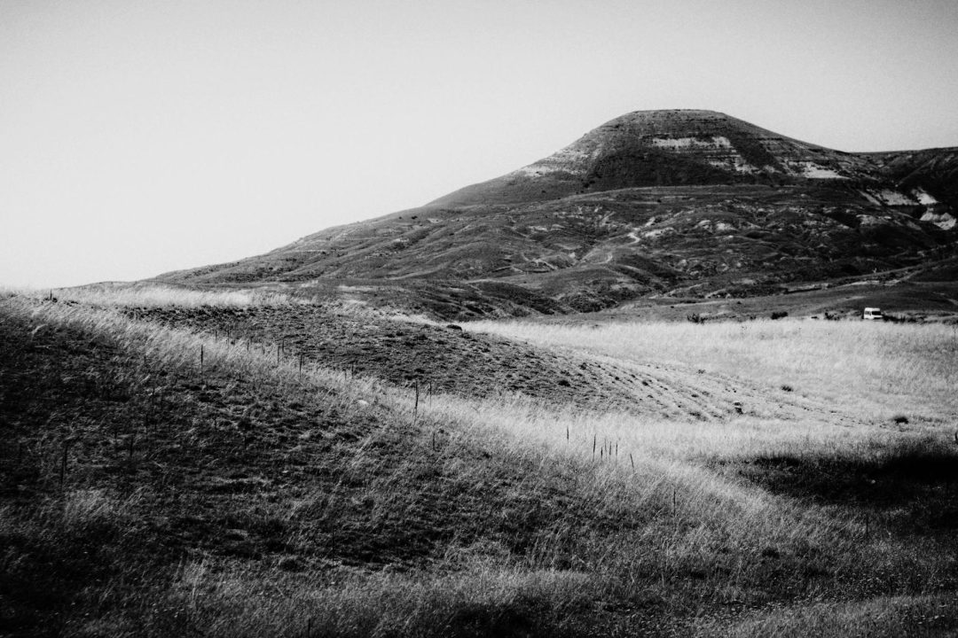 Dramatic black and white image of serene rolling hills and a distant mountain.