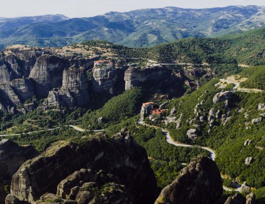 Breathtaking aerial view of Meteora's rocky landscape and monasteries in Greece under a clear sky.